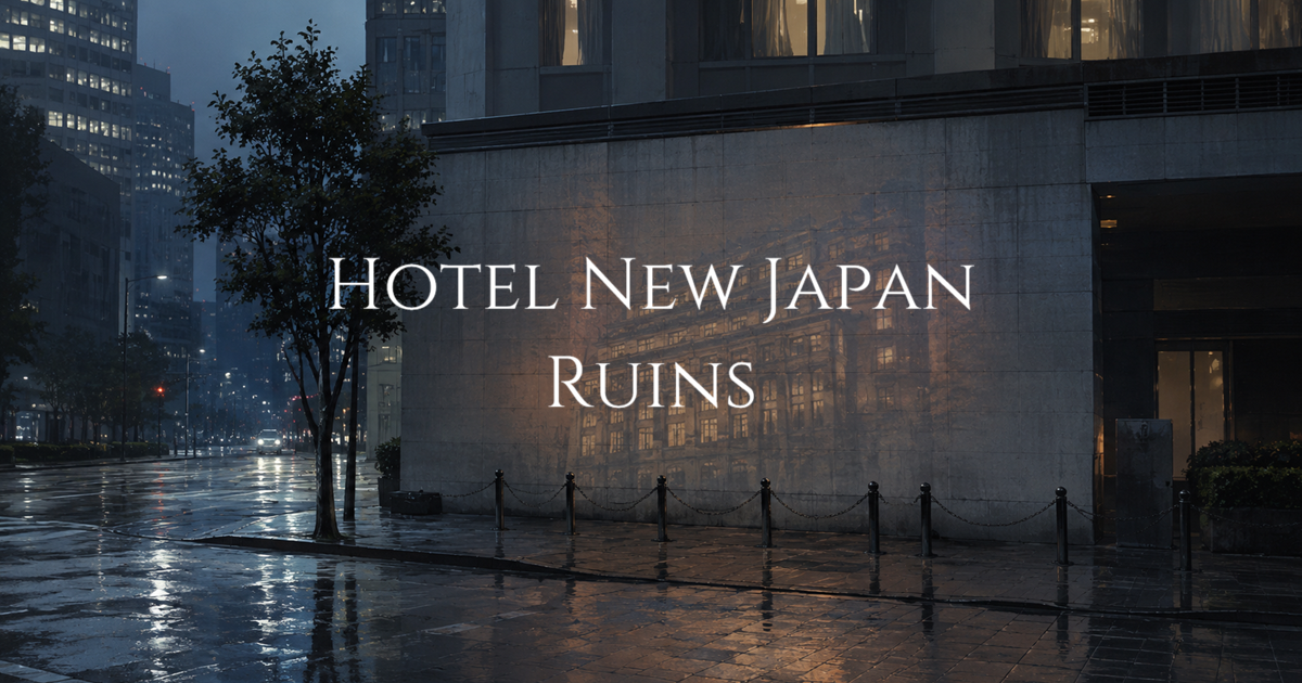 A rain-soaked Tokyo street beside a modern office building at dusk, with a faint reflection of an older hotel facade appearing on the wall.