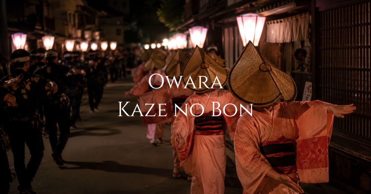 Women wearing woven hats perform the Owara Kaze no Bon dance along a lantern-lit street in Yatsuo at night.